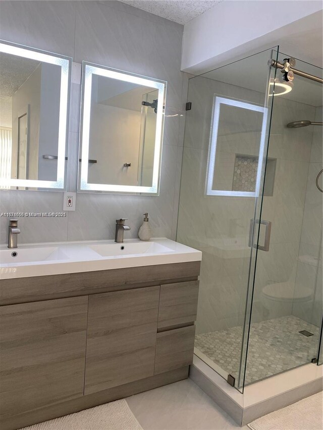 bathroom with walk in shower, vanity, a textured ceiling, and tile patterned floors