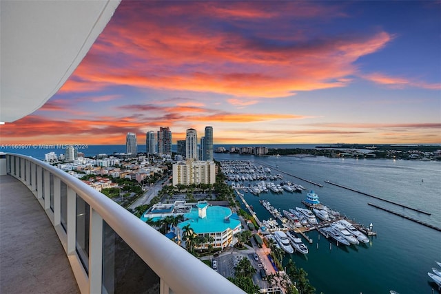 balcony at dusk featuring a water view