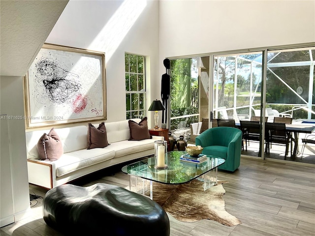 living room featuring light wood-type flooring and a towering ceiling