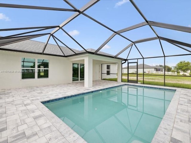 view of swimming pool with glass enclosure, a patio area, and a lawn