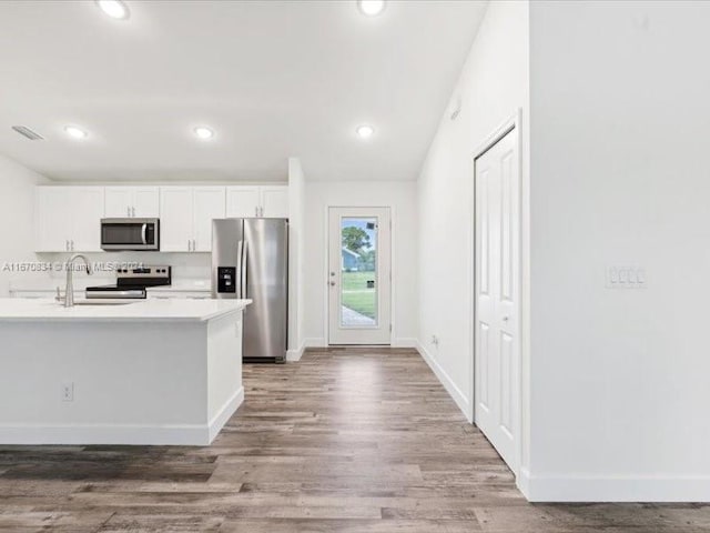 kitchen with appliances with stainless steel finishes, white cabinetry, sink, and hardwood / wood-style flooring