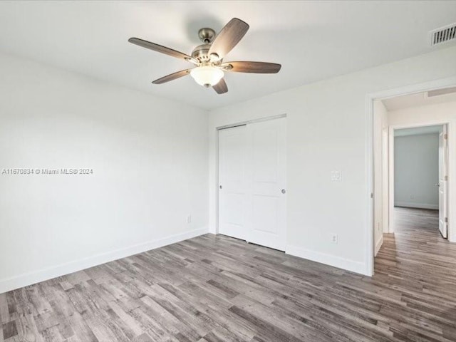 unfurnished bedroom featuring ceiling fan, hardwood / wood-style flooring, and a closet