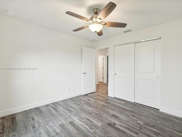 unfurnished bedroom with ceiling fan, a closet, and hardwood / wood-style floors