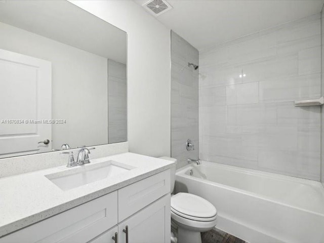 full bathroom featuring vanity, tiled shower / bath combo, and toilet