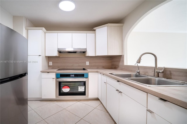 kitchen featuring appliances with stainless steel finishes, white cabinetry, tasteful backsplash, light tile patterned floors, and sink