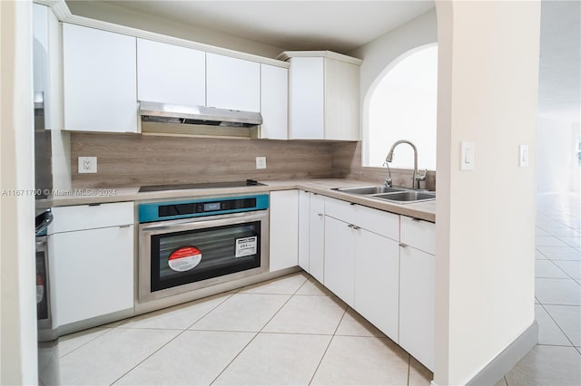 kitchen with oven, white cabinetry, sink, and light tile patterned floors