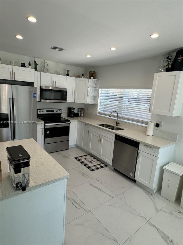 kitchen featuring light stone counters, white cabinets, stainless steel appliances, and sink