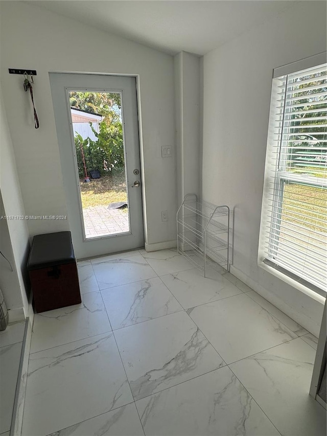 doorway to outside with lofted ceiling and a wealth of natural light