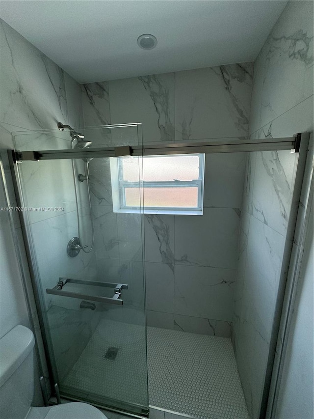 bathroom with a shower with door and toilet