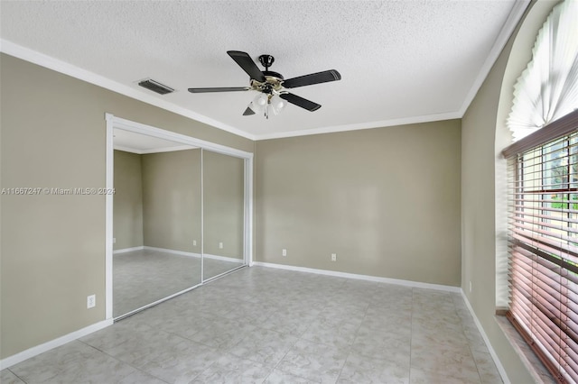 unfurnished bedroom with a closet, ceiling fan, a textured ceiling, and crown molding