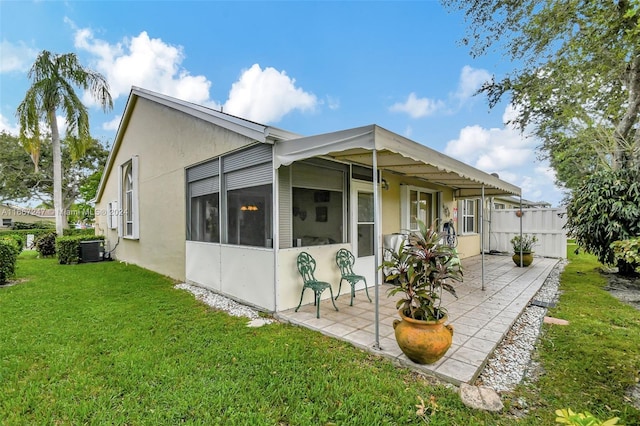 back of property with a patio, a lawn, a sunroom, and central AC unit