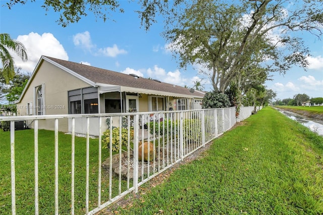 view of side of property with a sunroom, a lawn, and central air condition unit