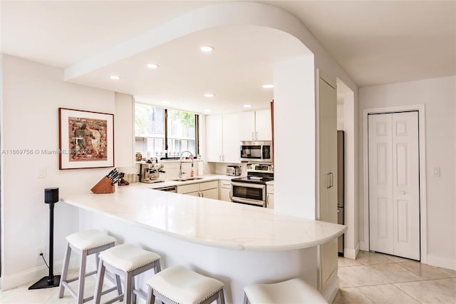 kitchen featuring a kitchen bar, kitchen peninsula, sink, and appliances with stainless steel finishes