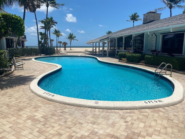 view of pool featuring a water view and a patio