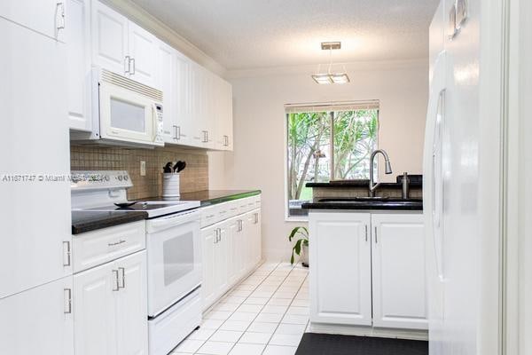 kitchen featuring white cabinets, light tile patterned floors, sink, white appliances, and backsplash