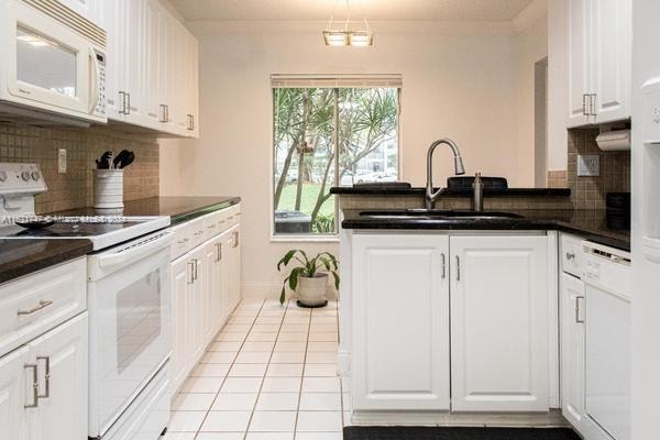 kitchen with white cabinets, backsplash, sink, and white appliances