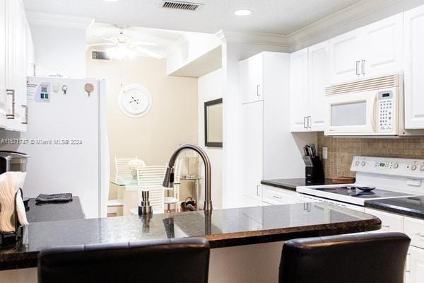 kitchen featuring kitchen peninsula, white appliances, and white cabinetry