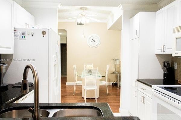 kitchen featuring white cabinets, ornamental molding, sink, white appliances, and dark hardwood / wood-style flooring