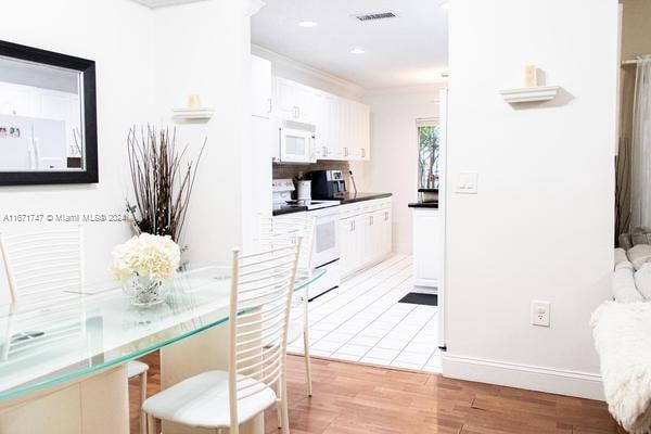 kitchen featuring light hardwood / wood-style floors, white appliances, and white cabinetry