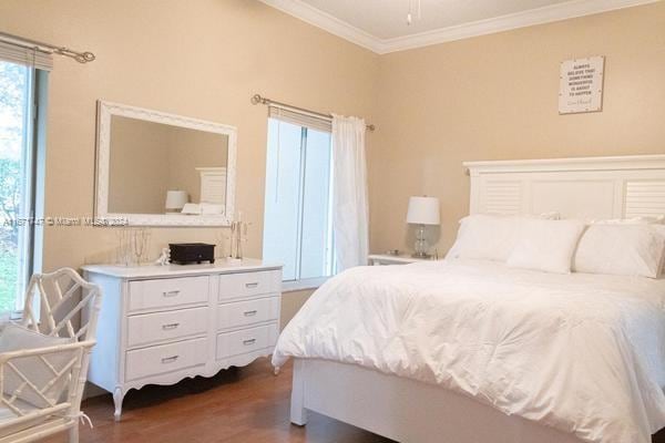 bedroom featuring ornamental molding and dark hardwood / wood-style flooring