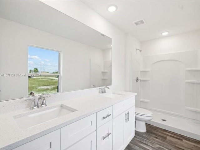 bathroom featuring vanity, a shower, hardwood / wood-style flooring, and toilet