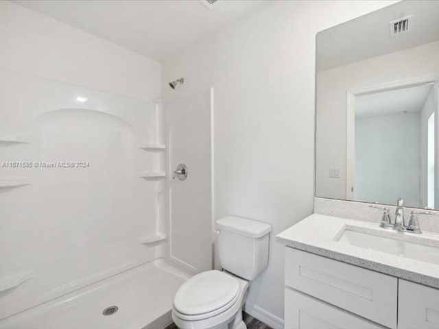 bathroom with vanity, toilet, and a shower