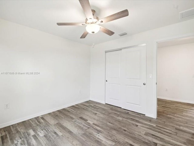 unfurnished bedroom featuring a closet, hardwood / wood-style flooring, and ceiling fan