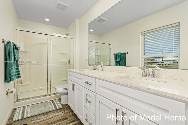 bathroom featuring toilet, a shower with shower door, hardwood / wood-style floors, and vanity