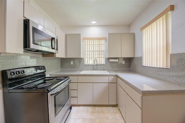 kitchen featuring light tile patterned floors, appliances with stainless steel finishes, sink, and decorative backsplash