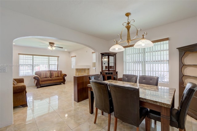 tiled dining area with ceiling fan with notable chandelier