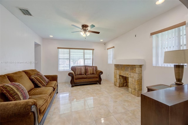 tiled living room with ceiling fan and a fireplace