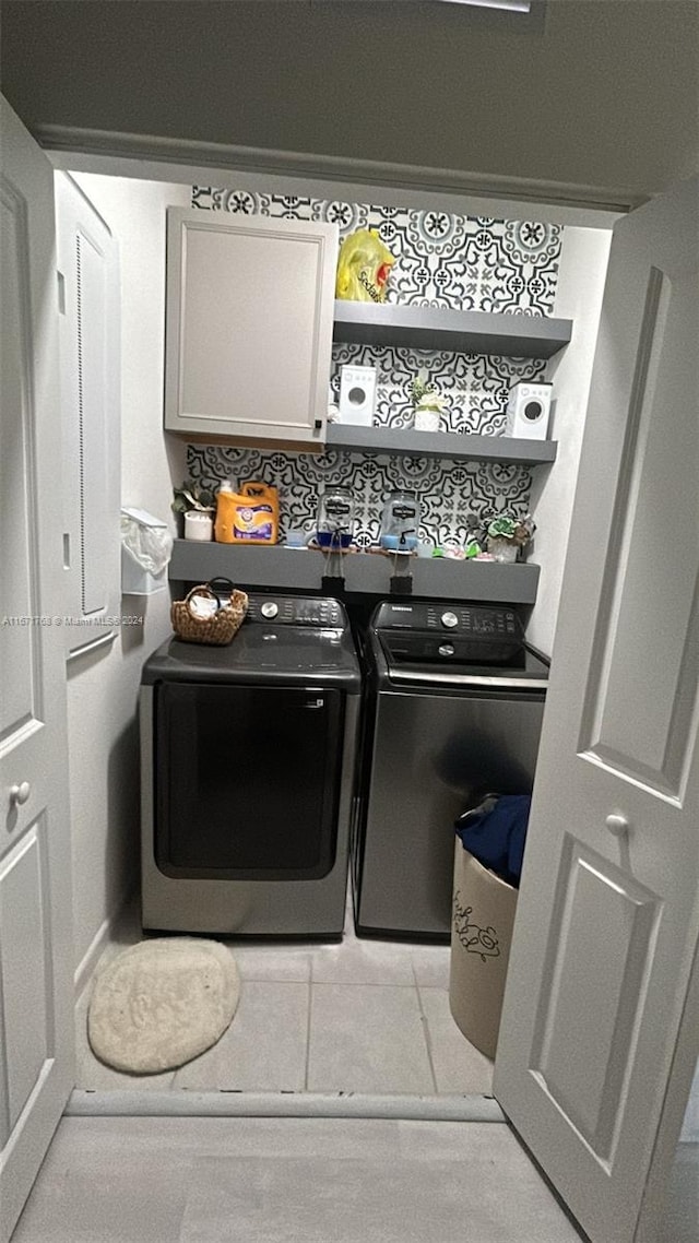 clothes washing area featuring cabinets and washer and clothes dryer