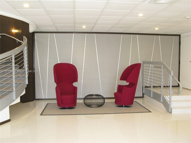 sitting room featuring a drop ceiling and tile patterned flooring