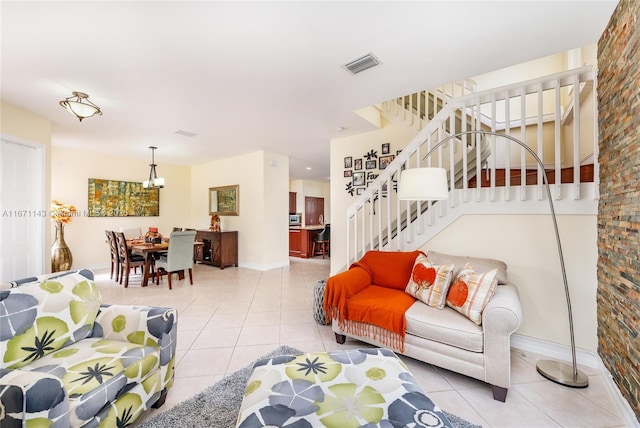 living room featuring light tile patterned floors, stairway, baseboards, and a chandelier