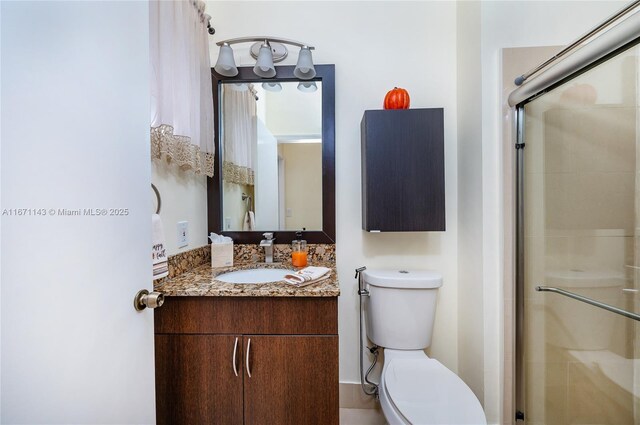 bathroom featuring a shower stall, toilet, and vanity