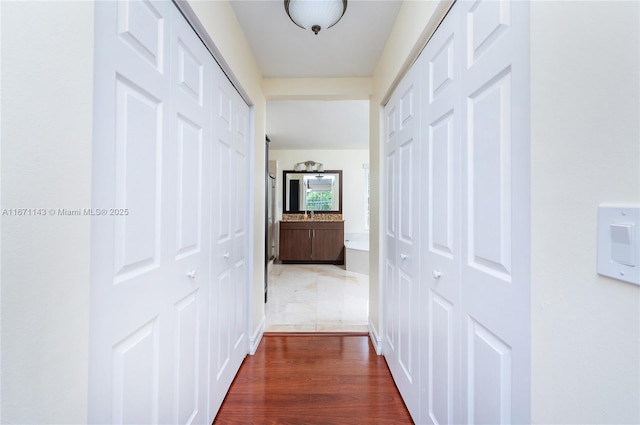corridor with dark wood-style floors and a sink
