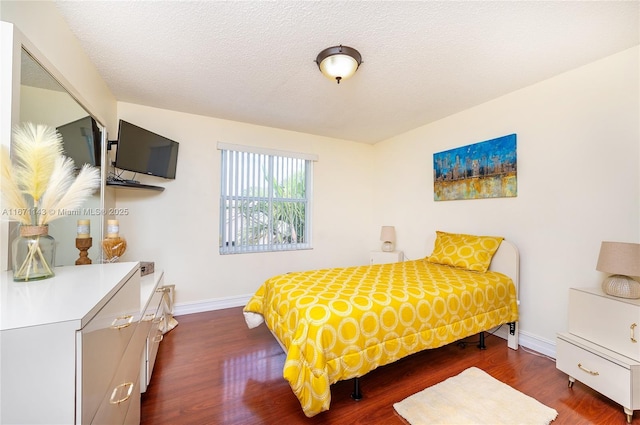 bedroom featuring baseboards, wood finished floors, and a textured ceiling