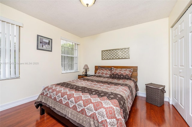bedroom featuring wood finished floors, baseboards, a closet, and a textured ceiling