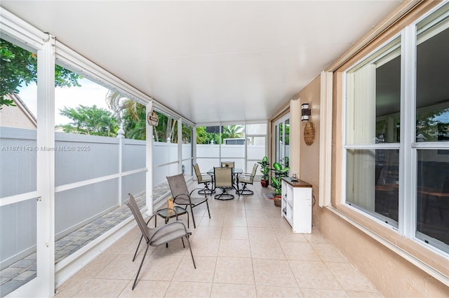 sunroom with outdoor dining area and tile patterned flooring