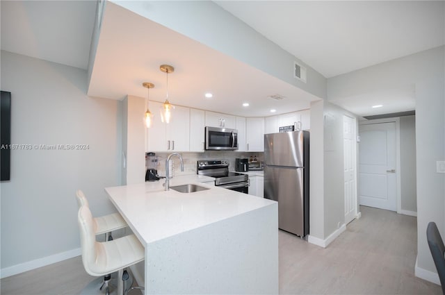 kitchen with hanging light fixtures, sink, kitchen peninsula, white cabinetry, and appliances with stainless steel finishes