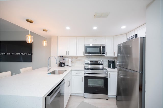 kitchen with sink, white cabinetry, kitchen peninsula, hanging light fixtures, and stainless steel appliances