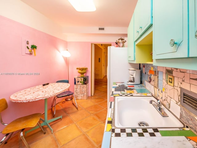 kitchen featuring decorative backsplash, light tile patterned flooring, and sink