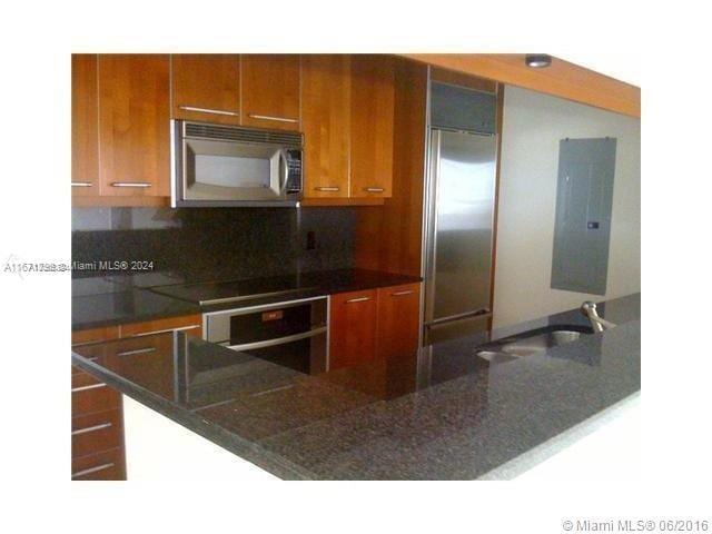 kitchen with electric panel, sink, kitchen peninsula, backsplash, and appliances with stainless steel finishes