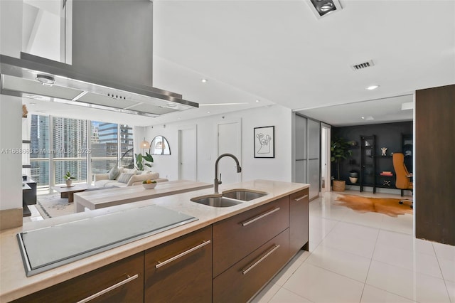 kitchen featuring island exhaust hood, light countertops, visible vents, open floor plan, and a sink