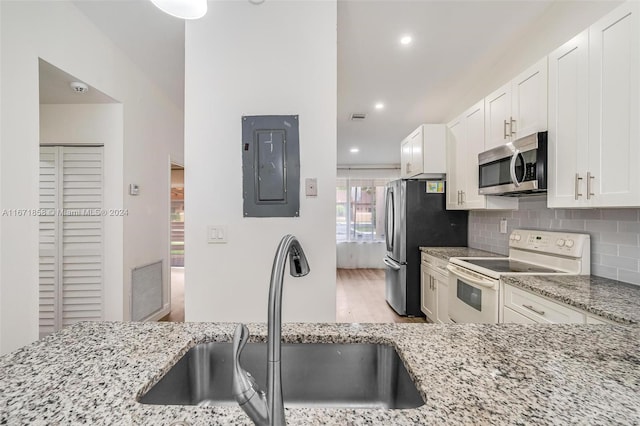 kitchen with appliances with stainless steel finishes, electric panel, a healthy amount of sunlight, and sink