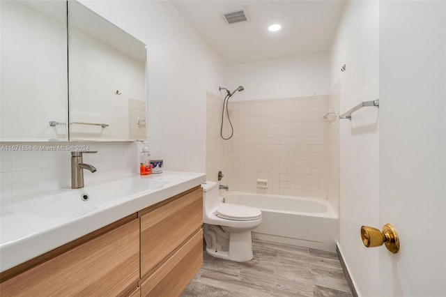 full bathroom with decorative backsplash, toilet, tiled shower / bath, hardwood / wood-style floors, and vanity