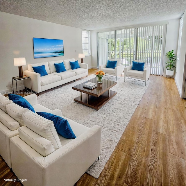 living room featuring a wall of windows, wood-type flooring, and a textured ceiling