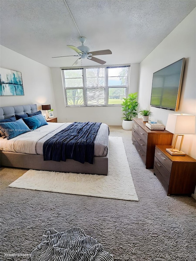 bedroom featuring ceiling fan, light colored carpet, and a textured ceiling