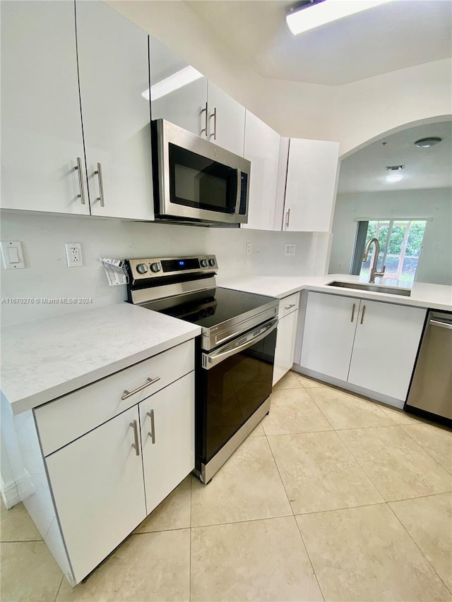 kitchen featuring stainless steel appliances, white cabinetry, light tile patterned floors, and sink