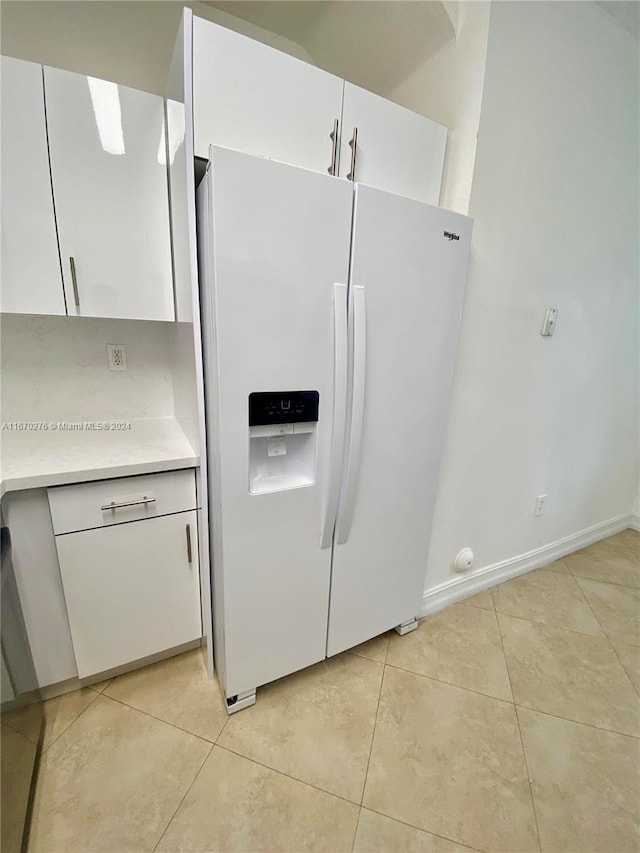 kitchen featuring white cabinets, white refrigerator with ice dispenser, and light tile patterned flooring